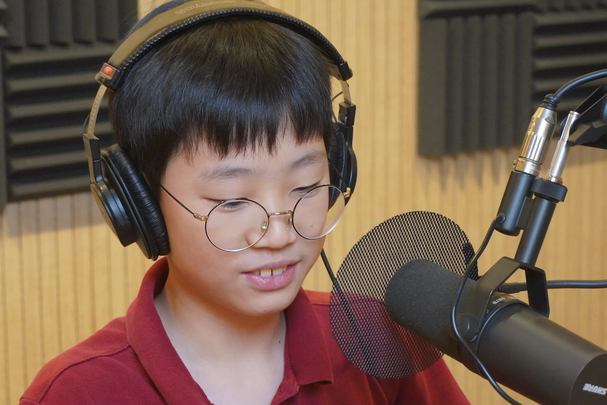 헤드폰을 쓰고 마이크 앞에서 녹음하는 학생